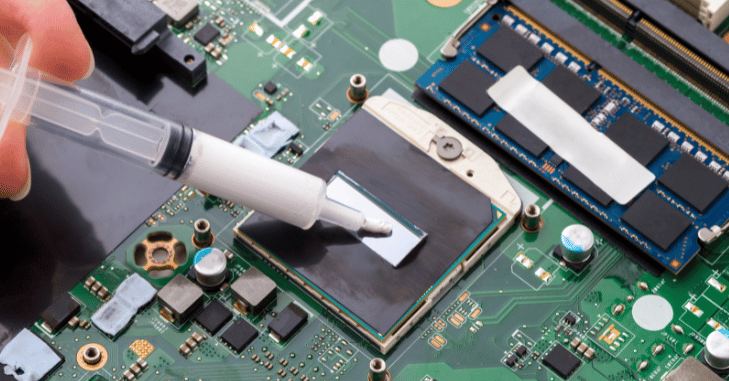 Syringe of thermal compound beside a CPU cooler